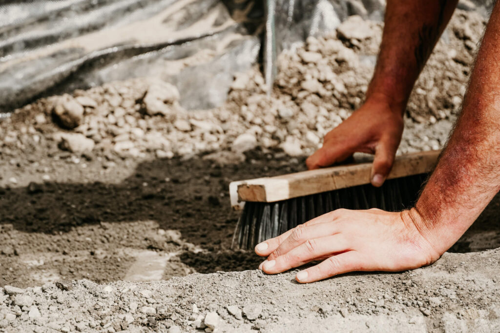 Close-up of an Earth and Turf Landscaping Edmonton worker brushing dirt away on a retaining wall work site.