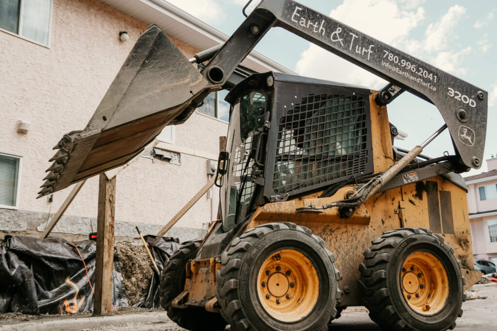 An Earth and Turf Landscaping Edmonton digger on a retaining wall job site.