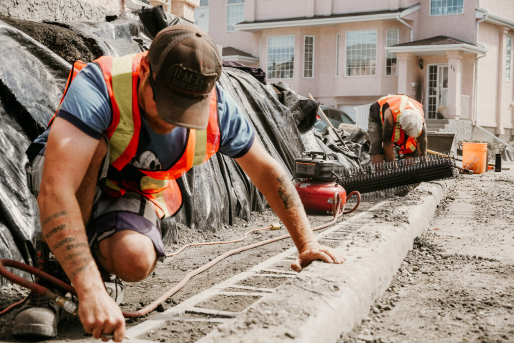 Two workers detailing a retaining wall project on an Earth and Turf Landscaping Edmonton job site.