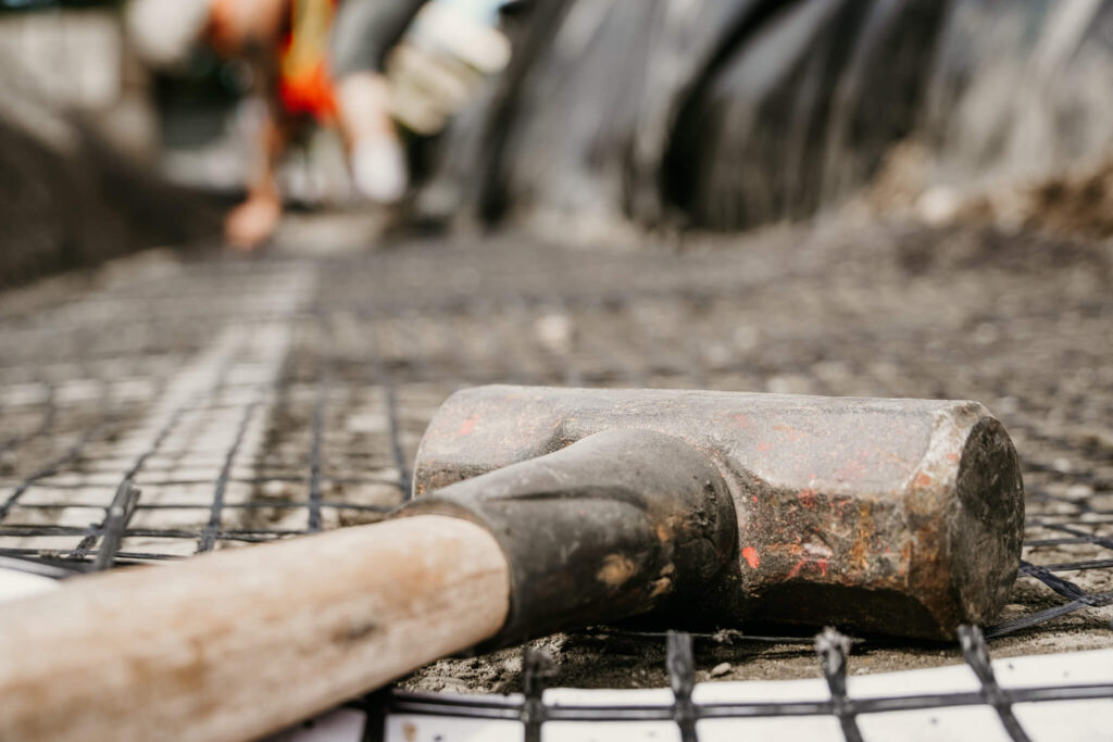 Close-up of a hammer sitting atop some wire mesh on an Earth and Turf Landscaping Edmonton retaining wall job site.