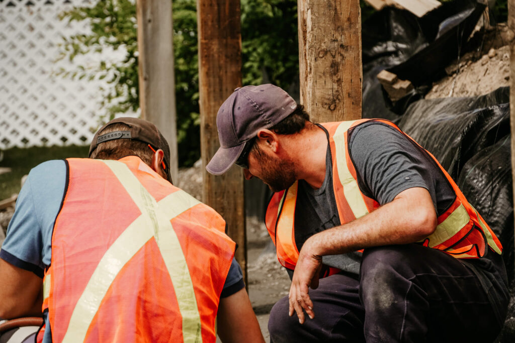 Two Earth and Turf Landscaping Edmonton workers discussing logistics on a retaining wall job site.