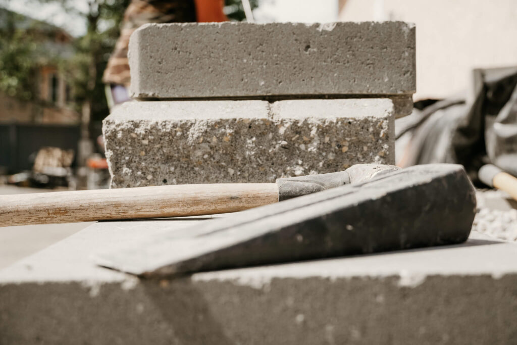 Side view (close-up) of a hammer and chisel sitting on top of an Earth and Turf Landscaping Edmonton retaining wall.