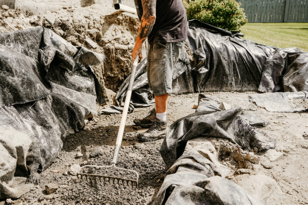 An Earth and Turf Landscaping Edmonton worker raking dirt.